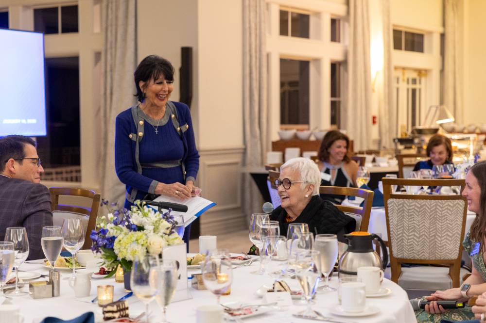 President Mantella smiling at event guest while she asks question to panelists